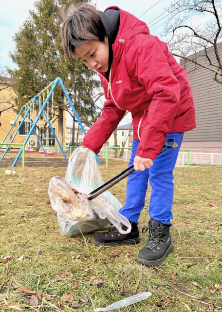 子供が公園のごみを拾っている写真