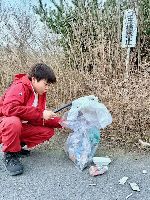 ごみ捨て禁止道路上のごみを拾う写真