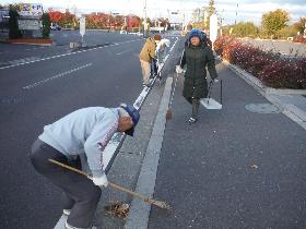 早朝に町内の住民が道路沿いの清掃活動（ゴミ拾いや草むしりなど）をしている様子の写真