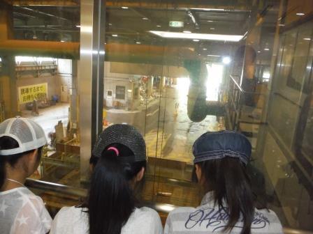 ガラス窓の奥の施設を見学している女の子3人の写真