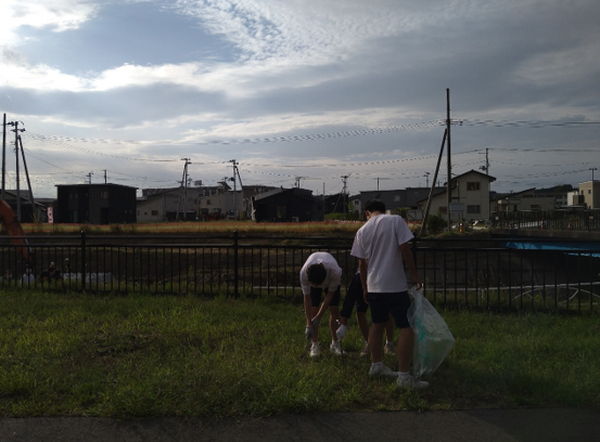 青空の広がる住宅地でゴミ拾いをする男子生徒二人の写真