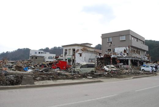 平成23年4月2日：手前の瓦礫が撤去され道路が整備されているが赤い自動車、軽自動車は残っている、奥に住宅が3棟立っている写真