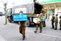 自衛隊の車両からパレットに積まれた荷物を運ぶ2名の自衛隊員の写真