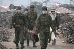 瓦礫を運ぶ5名の自衛隊員が手前に向かって歩いている、奥には瓦礫の山が写っている写真