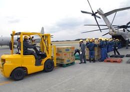 フォークリフトを使って自衛隊の大型ヘリコプターからの荷物を運び出している写真