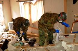 瓦礫が散乱する家屋内で下を向いて捜索をしている自衛隊員2名の写真