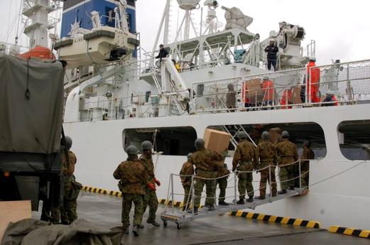 船から物資をリレー方式で陸地に運ぶ自衛隊員たちの写真