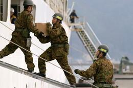 船から地上にリレー方式で物資を運ぶ自衛隊員3名の写真