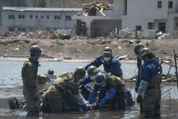 川の中から瓦礫をひっぱろうとする自衛隊員数名の写真