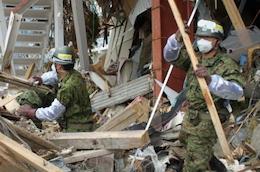 崩れかけた家屋の木材を撤去している自衛隊員2名の写真