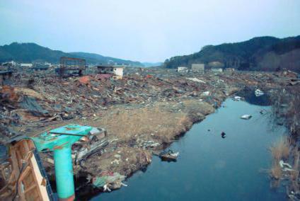 4月1日：手前に緑の鉄柱、左に瓦礫の山、右には川が流れている写真