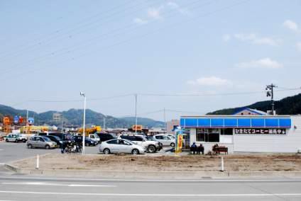 5月8日：被災した町の様子（左に数十台の車が駐車されている、右にコンビニ、中央の瓦礫が撤去されている）