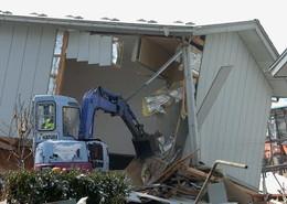 被災した家をショベルカーで壊している写真