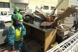 トラックの荷台に積まれた瓦礫と荷台に乗り込んでいる作業員2名の写真