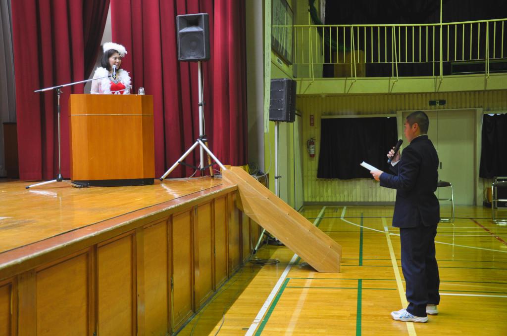 舞台下で代表であいさつをしている男子生徒と、舞台の上で話を聞いている吉岡さんの写真