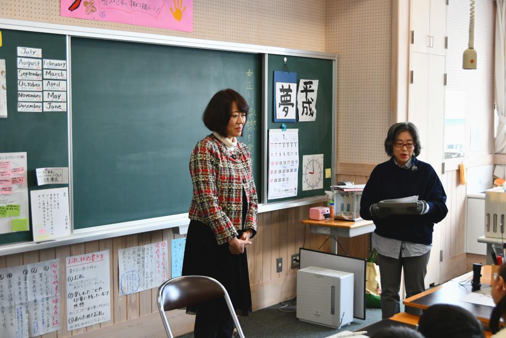 教室前方に紙を見ている女性と、黒板の前に立っている梅内さんの写真