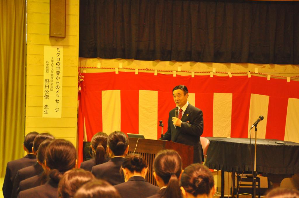 演台の前に立ってマイクを持った話をしている野田先生の写真
