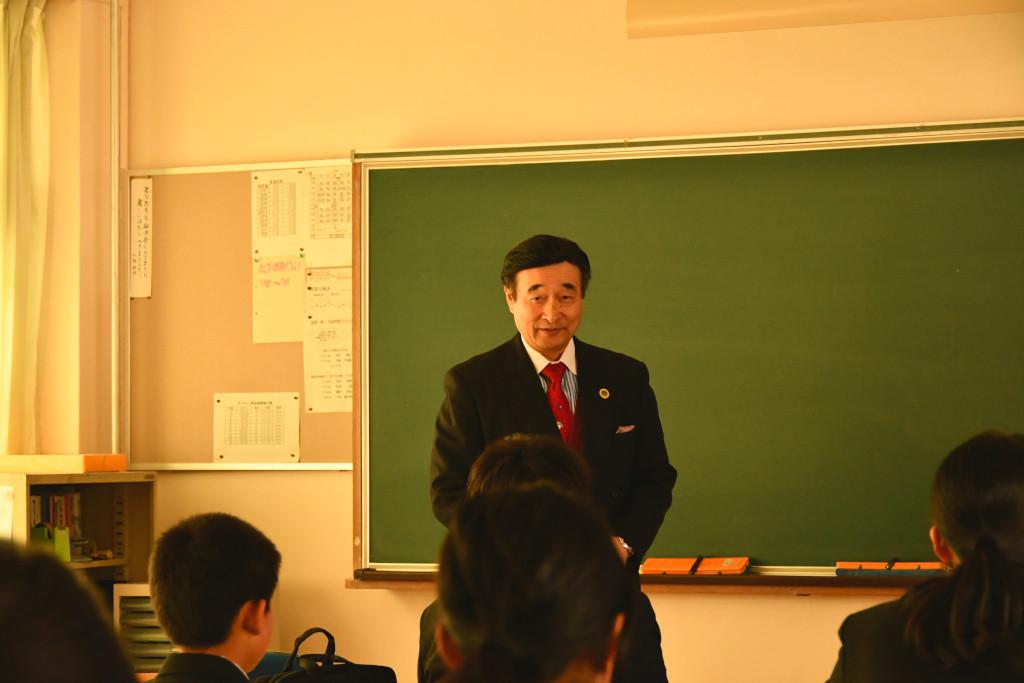 黒板の前に立って話をしている野田先生の写真