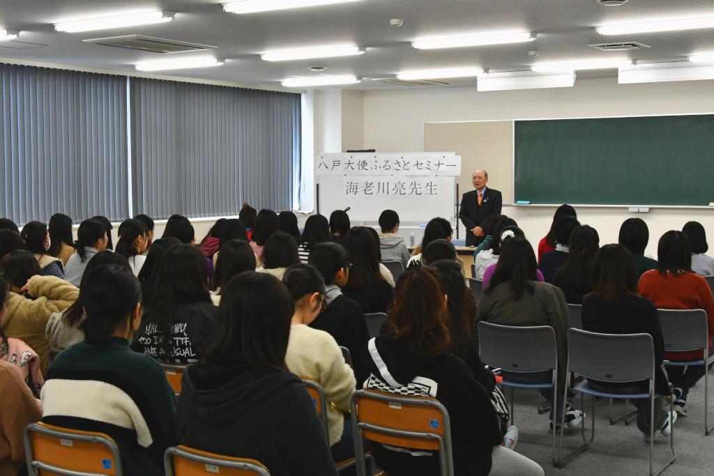 着席している学生たちの後姿と前で話をしている海老川さんを、後方から撮影した写真