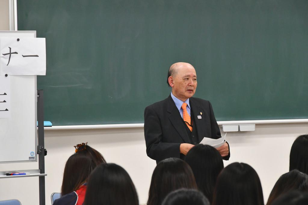 黒板の前で紙を手に持ちながら話をしている海老川さんの写真
