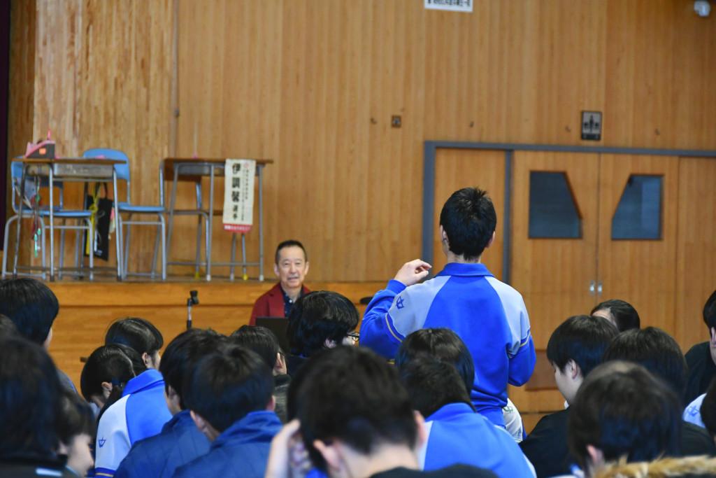 立って質問をしている生徒の後姿と、生徒の話を聞いている関橋さんの写真