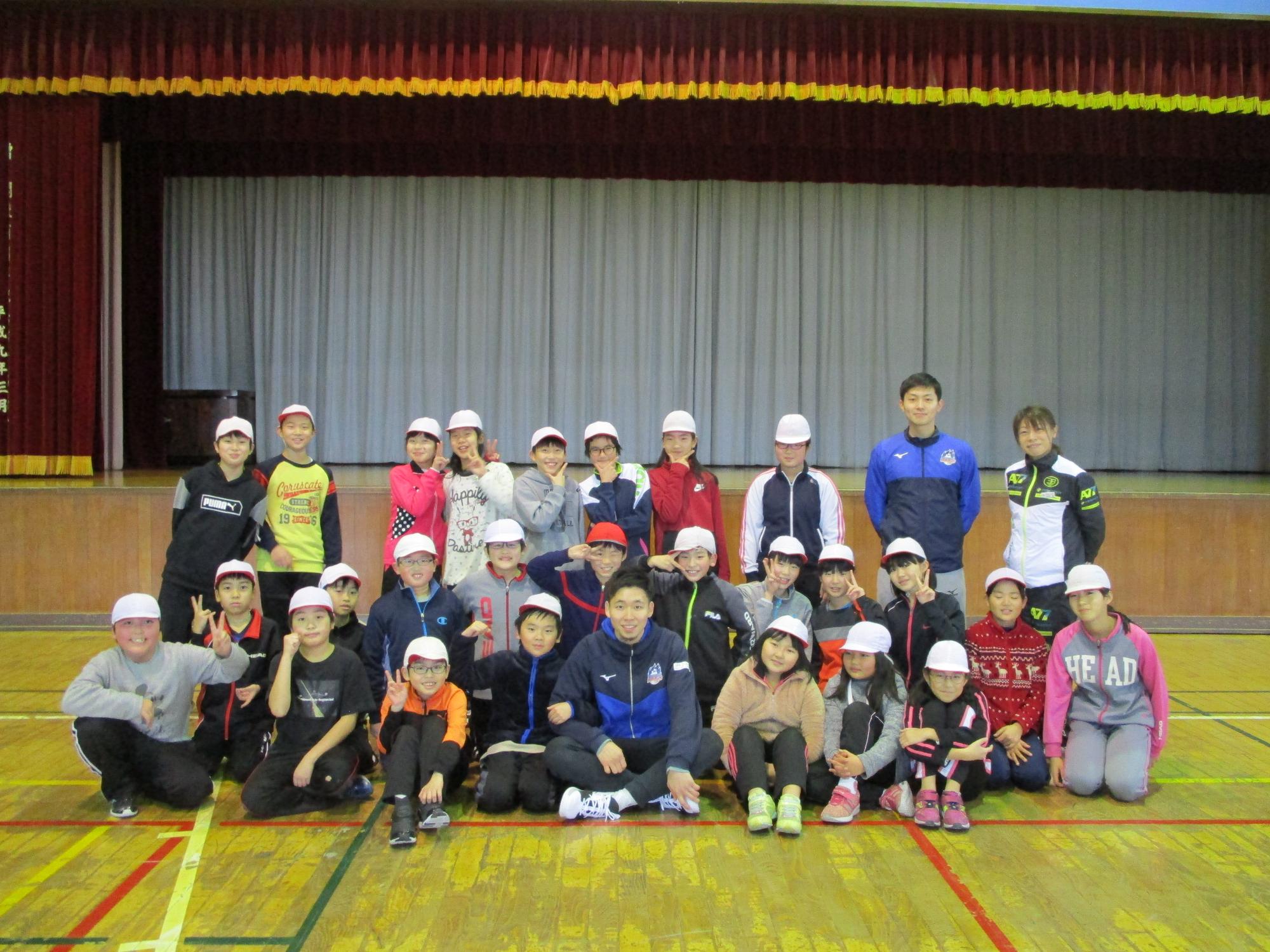 子どもたちが、野里選手、鈴木コーチと一緒に記念撮影をしている様子