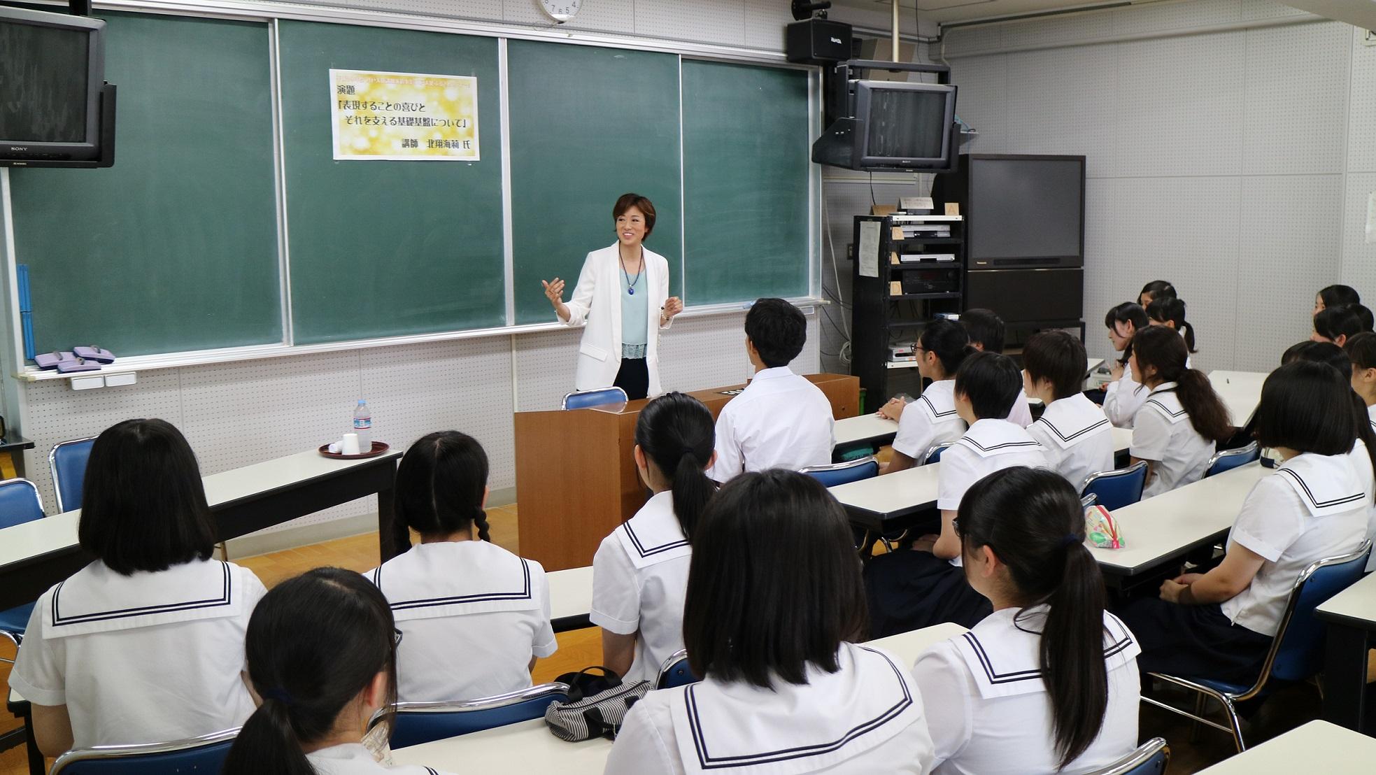 教室で着席している生徒たちの後姿と、前で身振りをしながら話をしている北翔さんの写真