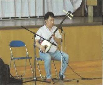 椅子に座って三味線を弾いている松田さんの写真