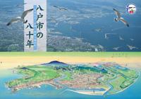 紙面のイメージ：縦書きで上部に八戸市の八十年のテキスト、左にカモメが飛んでいる、背景に町の写真、下に町の様子を上空から描かれている紙面のイメージ