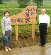 「八戸大使館」の看板の両脇に立っている林 芳輝さんと女性の写真