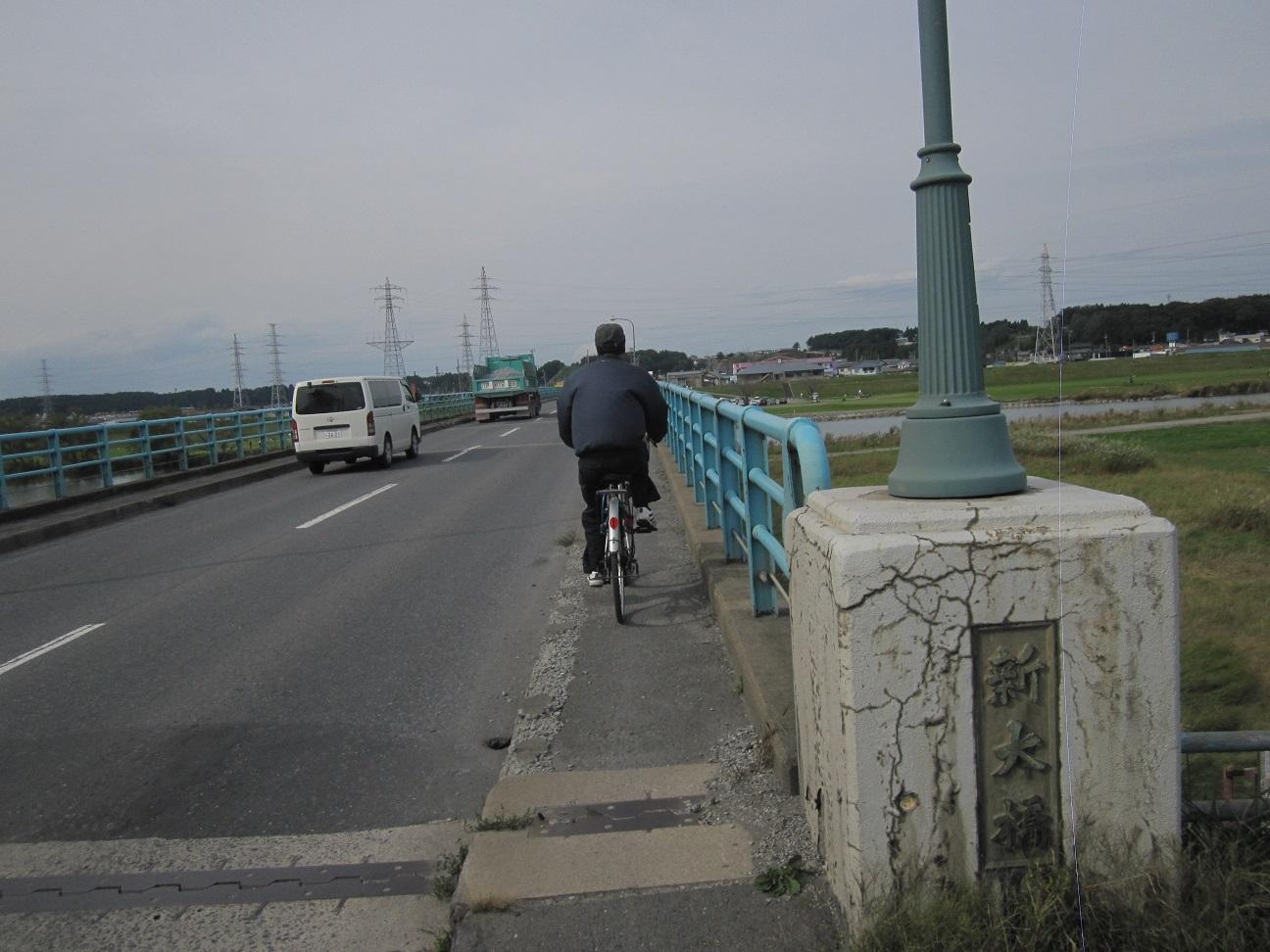 車と自転車に乗った人が新大橋を走っている写真