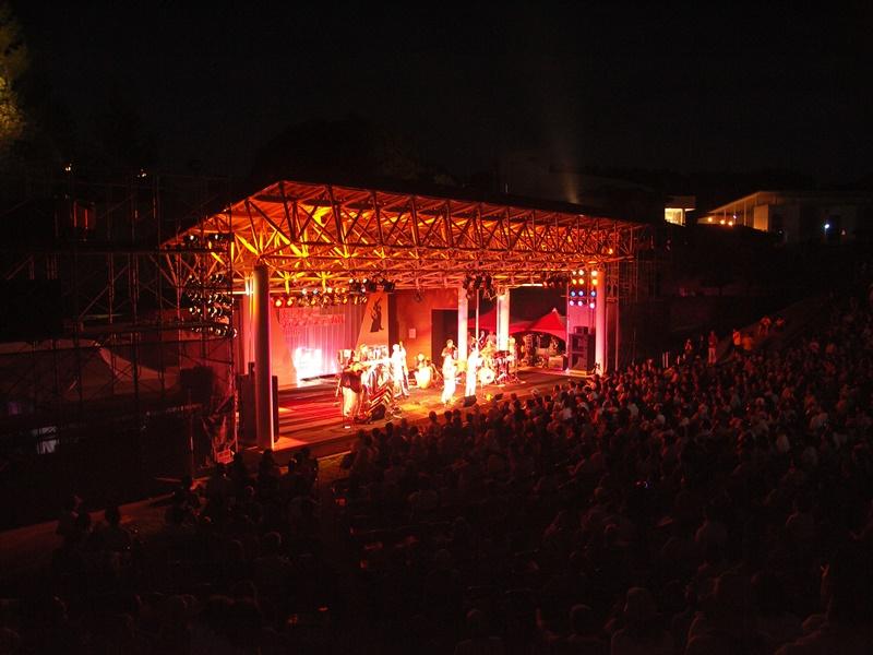 会場の斜め後方から赤く照らされたステージを写した写真