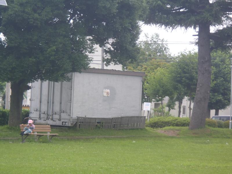 ベンチが設置されている場所の奥にある白い倉庫の写真
