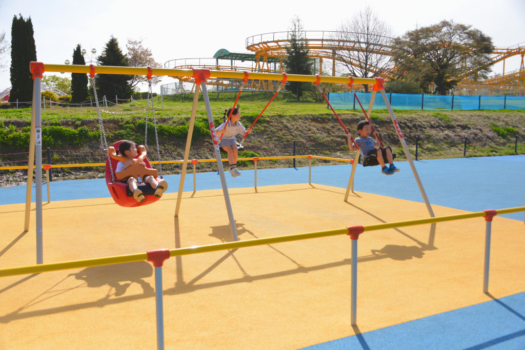大型複合遊具広場内に設置された3連サポート付ブランコの写真