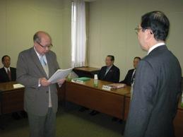 八戸市学校適正配置検討委員会委員長が書類を提出する様子の写真