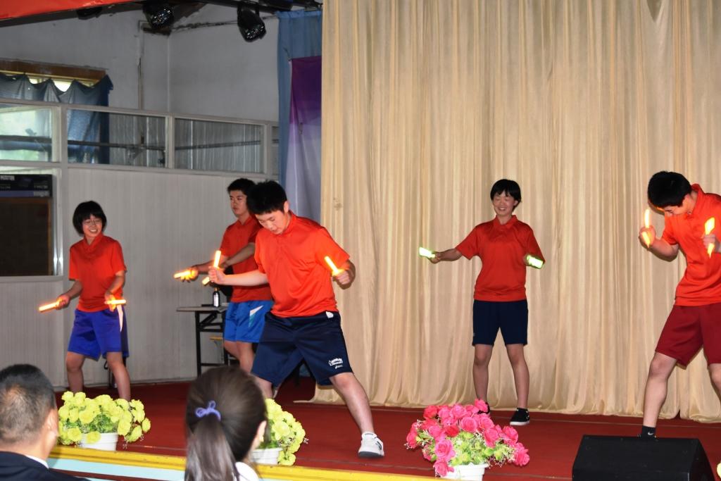 赤い服を着てペンライトをもって舞台で踊っている生徒たちの写真