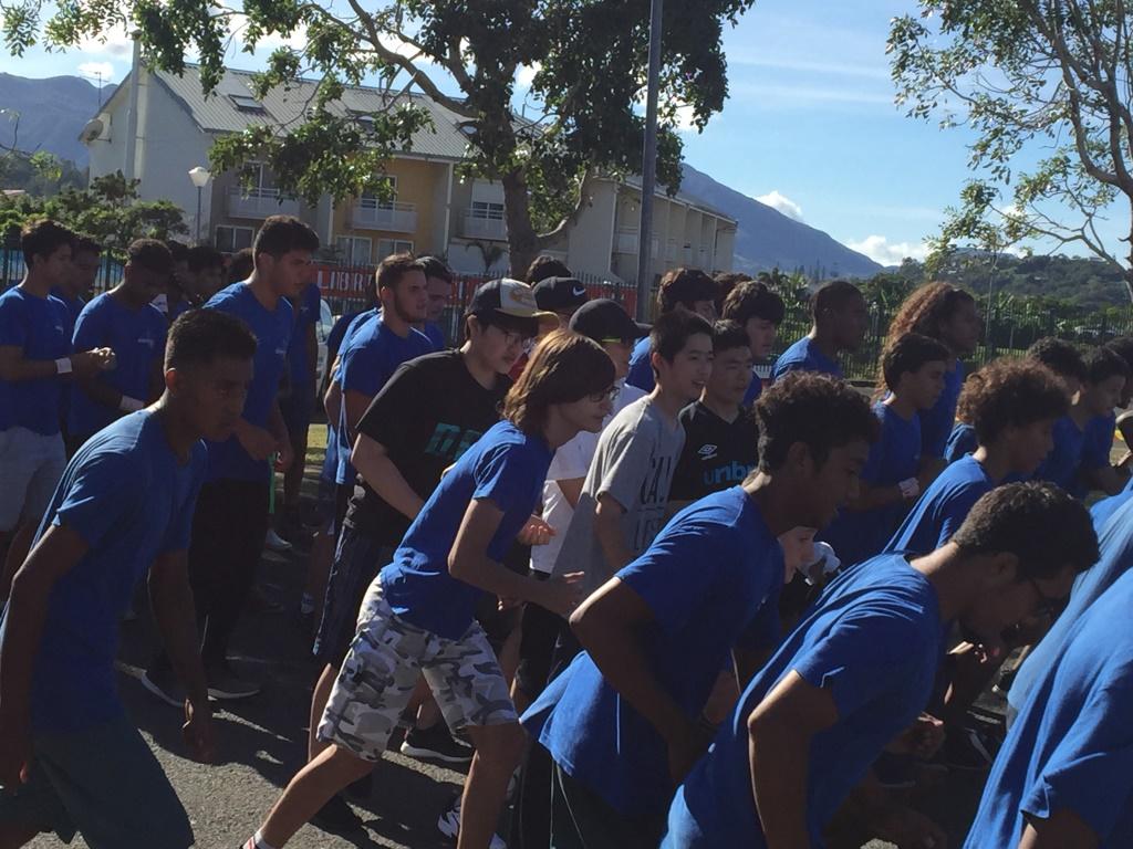 青い制服の現地の生徒たちと一にが右に向かってマラソンをしている生徒たちの写真