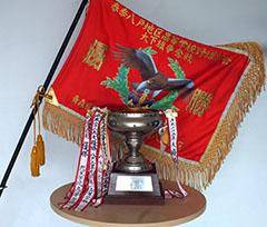 金の室岡杯と赤い大下旗が並べられた写真