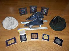 モットーとする言葉の書かれた盾、スケート靴五輪の帽子、グルノーブルで購入した愛用の帽子、受賞メダルが並べられた写真