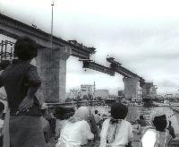 橋の完成を見上げる人々の写真