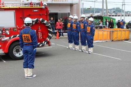 消防車の前に4名が整列し開始の合図を待っている写真
