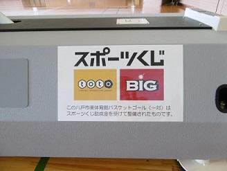 八戸市東体育館に設置されたバスケットゴールの土台に貼られたスポーツくじの看板の写真