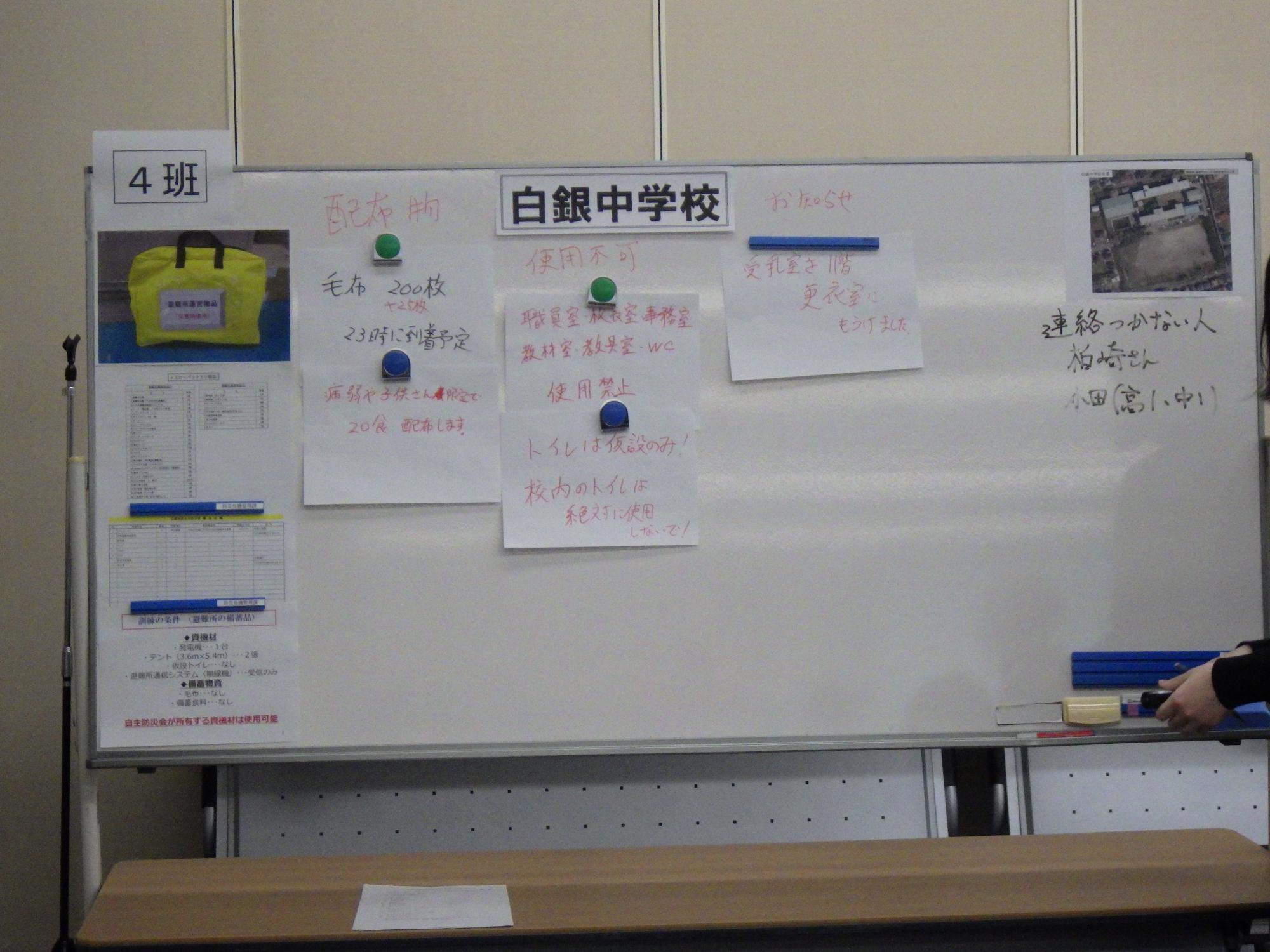 白銀中学校と書かれたホワイトボードに、避難所での連絡事項等の掲示物が貼られている写真
